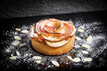 Apple tart with a rose made of apples on a dark surface