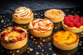 Assorted tarts with decorative elements on a dark surface