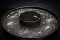 Black dessert on a black plate with gold flakes on a dark background