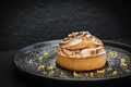 Pastry with meringue on a black plate against a dark background