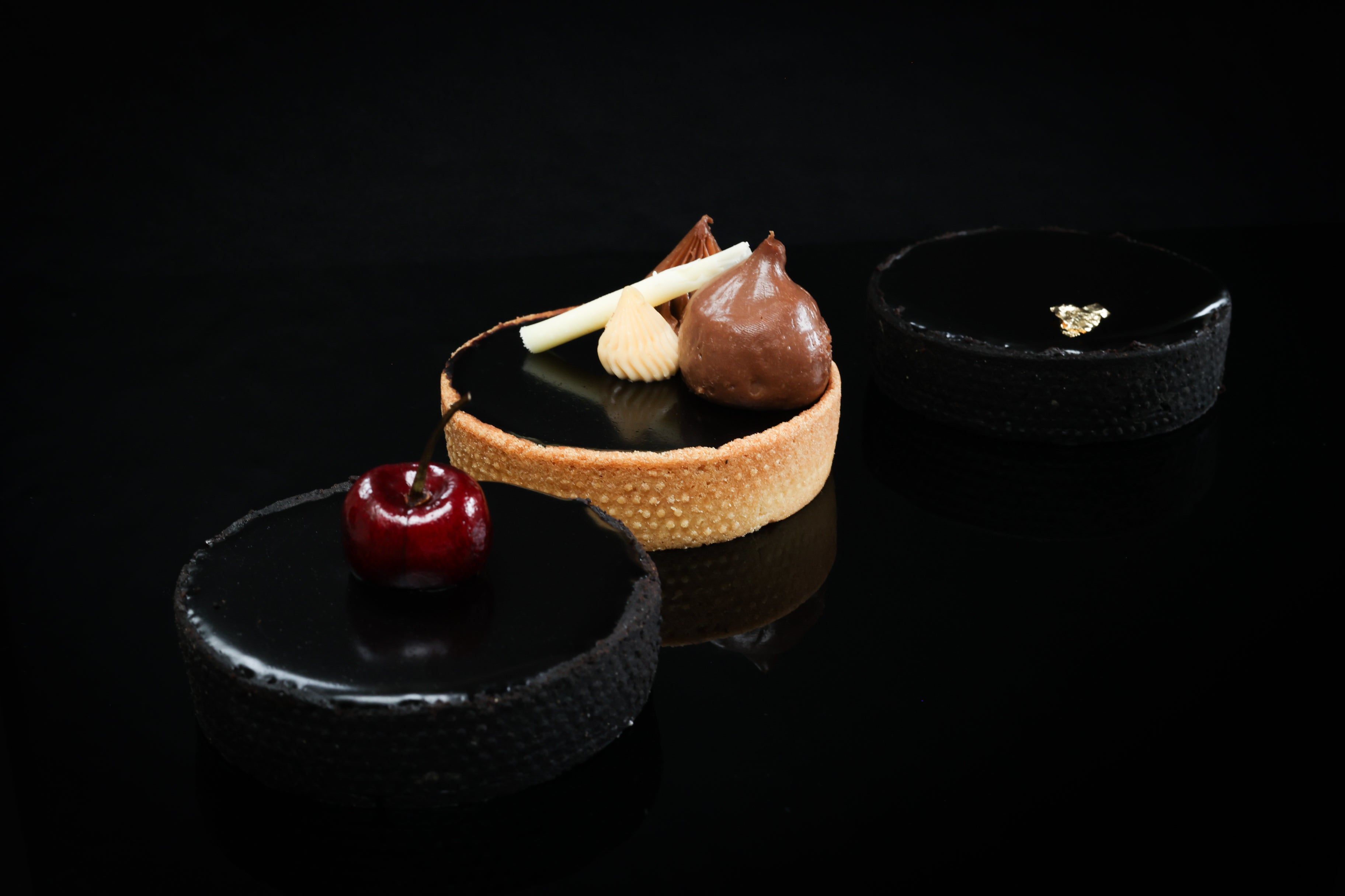 Delicate dessert with a tartlet, chocolate mousse, and cherry on a black background